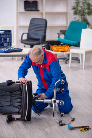 Old male repairman repairing office chairの写真素材