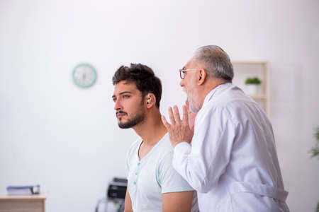 Young male patient with hearing problem visiting old doctor otor