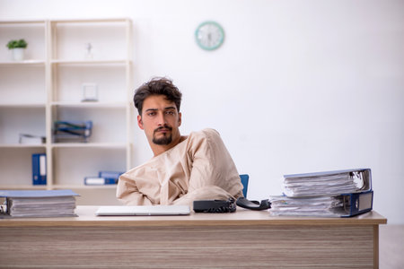 Crazy young man in straitjacket at the officeの写真素材