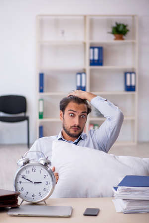 Young male employee in oversleeping conceptの写真素材
