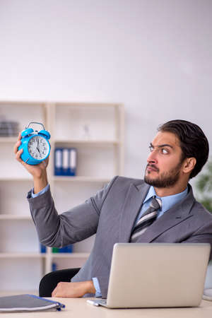 Young male employee in time management conceptの写真素材