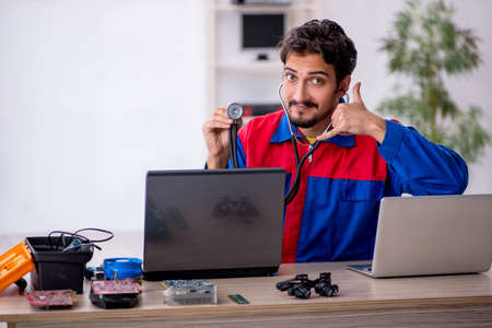 Young male repairman repairing computer