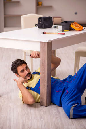 Young male carpenter repairing table at homeの写真素材
