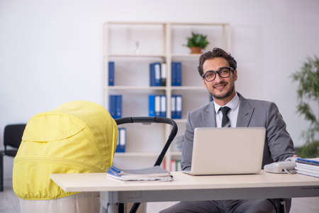 Young male employee looking after new born at workplaceの写真素材