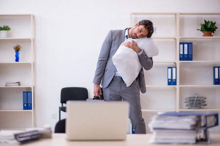 Young male employee in oversleeping conceptの写真素材