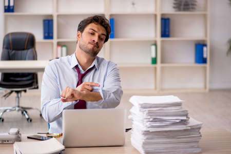Young male employee and too much work in the officeの写真素材