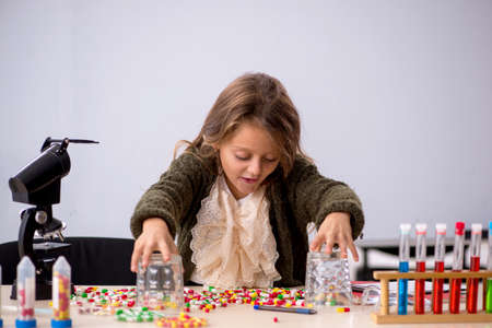 Young little girl chemist in drugs synthesis concept