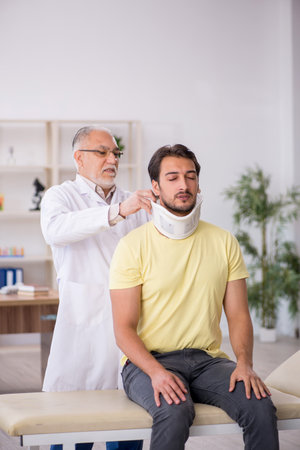 Young male neck injured patient visiting old male doctorの写真素材