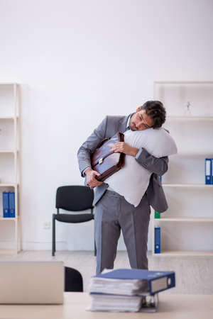 Young male employee in oversleeping conceptの写真素材