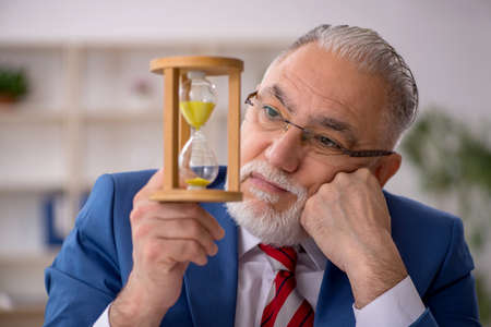 Old male employee in time management conceptの写真素材