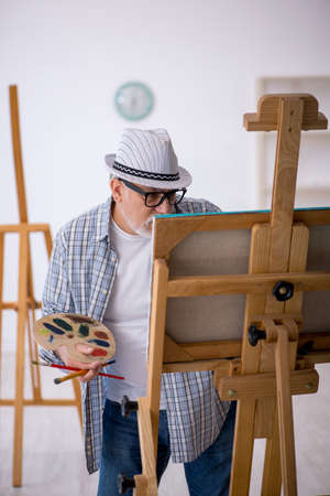 Old man enjoying painting at homeの写真素材