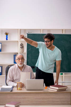 Old male teacher and young male student in remuneration conceptの写真素材