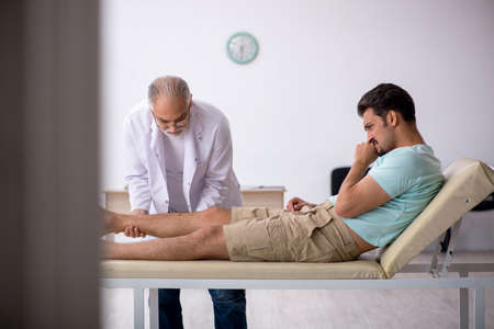Young male patient visiting old male doctorの写真素材