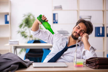 Young alcohol addicted employee sitting in the officeの写真素材