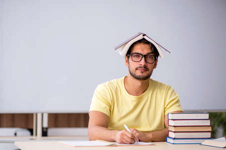 Young male student preparing for exams in the classroom