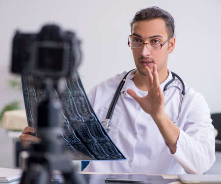 Young male doctor radiologist recording video for his blogの写真素材
