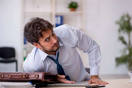 Young male employee in oversleeping conceptの写真素材