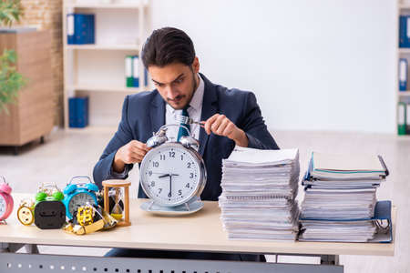 Young businessman employee eating alarm-clockの写真素材