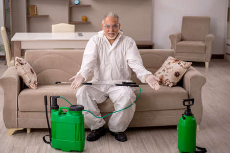 Old male contractor doing pest control at homeの写真素材