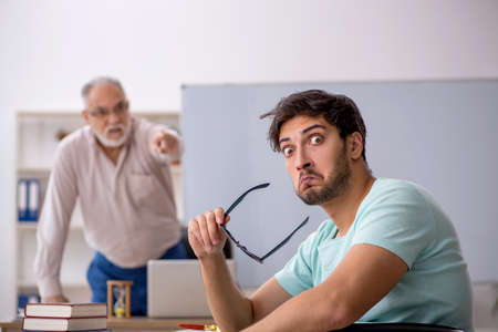 Old male teacher and young male student in the classroomの写真素材