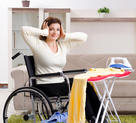 Woman in wheelchair ironing at homeの写真素材