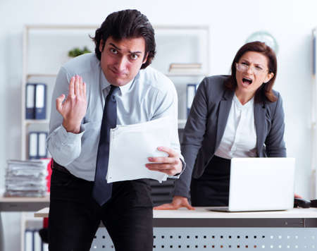 Old female boss and young male employee in the officeの写真素材