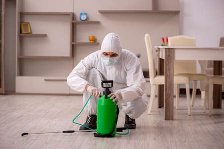 Young male contractor doing pest control at homeの写真素材