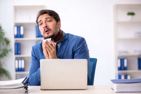 Young male employee suffering at workplaceの写真素材