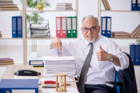 Old male employee in time management conceptの写真素材