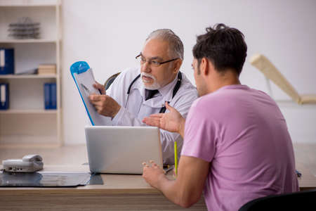 Young male patient visiting old male doctorの写真素材