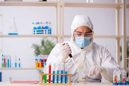 Young male chemist working at the lab during pandemicの写真素材