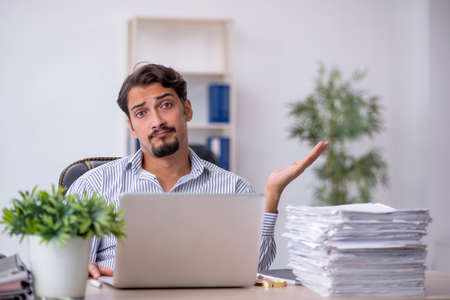 Young male employee unhappy with excessive work in the officeの写真素材