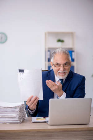 Old male employee and too much work in the officeの写真素材