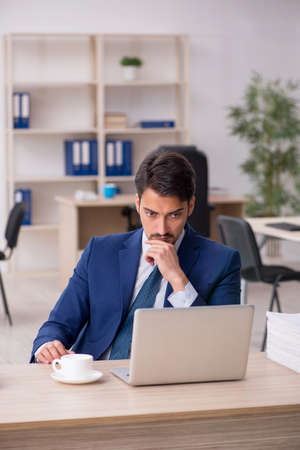 Young male employee and too much work in the officeの写真素材