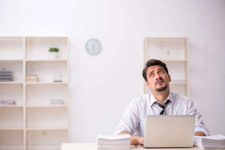 Young male employee unhappy with excessive work in the officeの写真素材