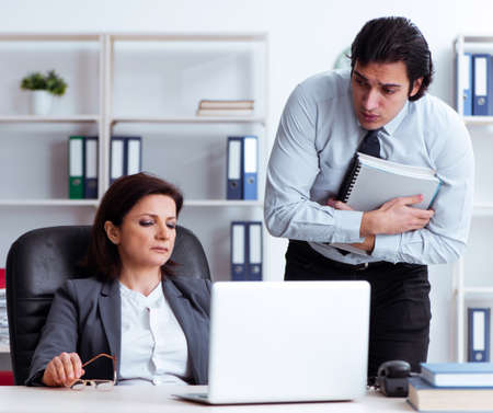 Old female boss and young male employee in the officeの写真素材