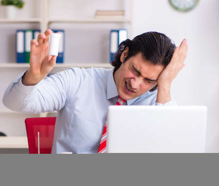 Young male employee suffering in the officeの写真素材