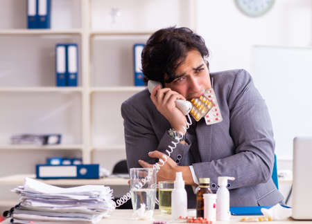 Man with flu working in the officeの写真素材
