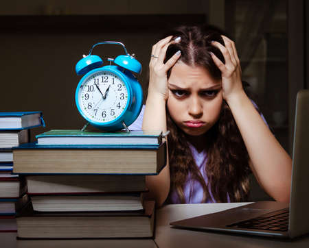 Young female student preparing for exams late at homeの写真素材