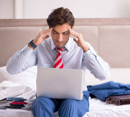 Young employee working at home sitting on the bedの写真素材