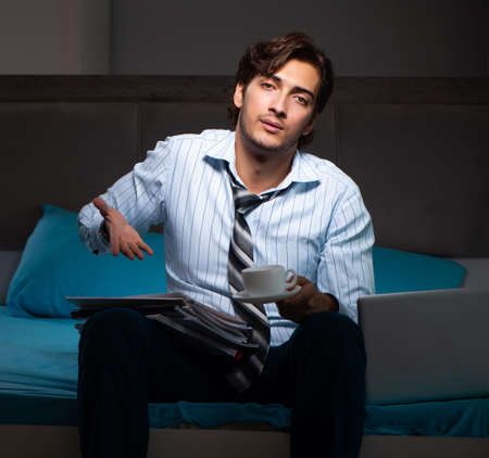 Tired businessman working overtime at home at nightの写真素材