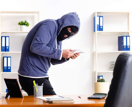 Male thief in balaclava in the officeの写真素材