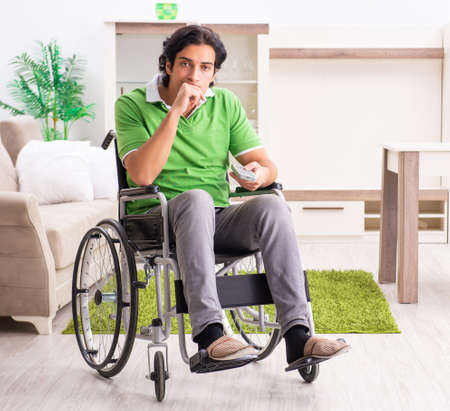 Young handsome man in wheelchair at homeの写真素材