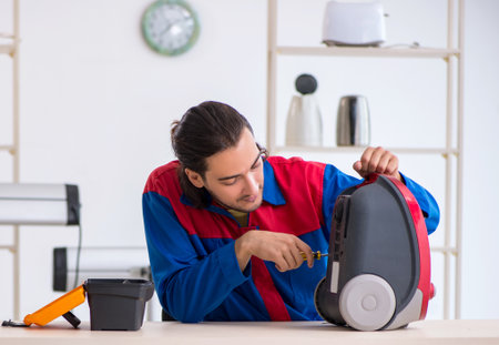 Young male contractor repairing vacuum cleaner at workshopの写真素材