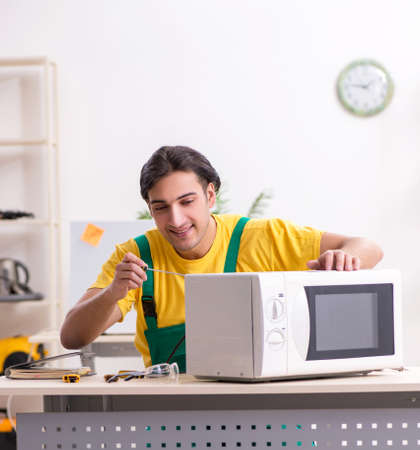Young repairman repairing microwave in service centreの写真素材