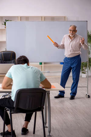 Old male teacher and young male student in the classroomの写真素材
