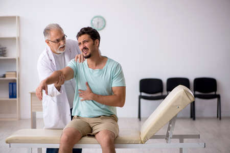 Young male patient visiting old male doctorの写真素材