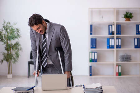 Young male employee after car accident working in the officeの写真素材