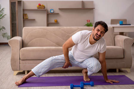Young man doing sport exercises at homeの写真素材