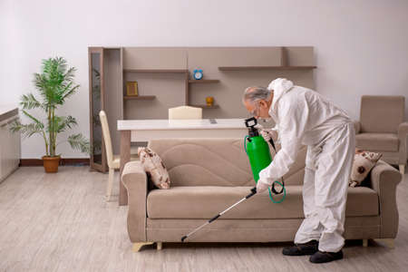 Old male contractor doing pest control at homeの写真素材